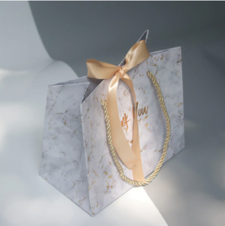 Geschenktüte im Marmor-Design mit goldener Schleife